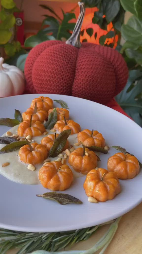 This may contain: small pumpkins on a plate with cream sauce and green beans in the middle, surrounded by leaves