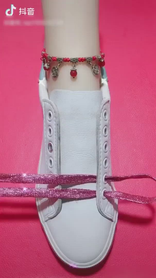 This may contain: a pair of white sneakers with pink bows tied around the toe and red beads on each shoelace