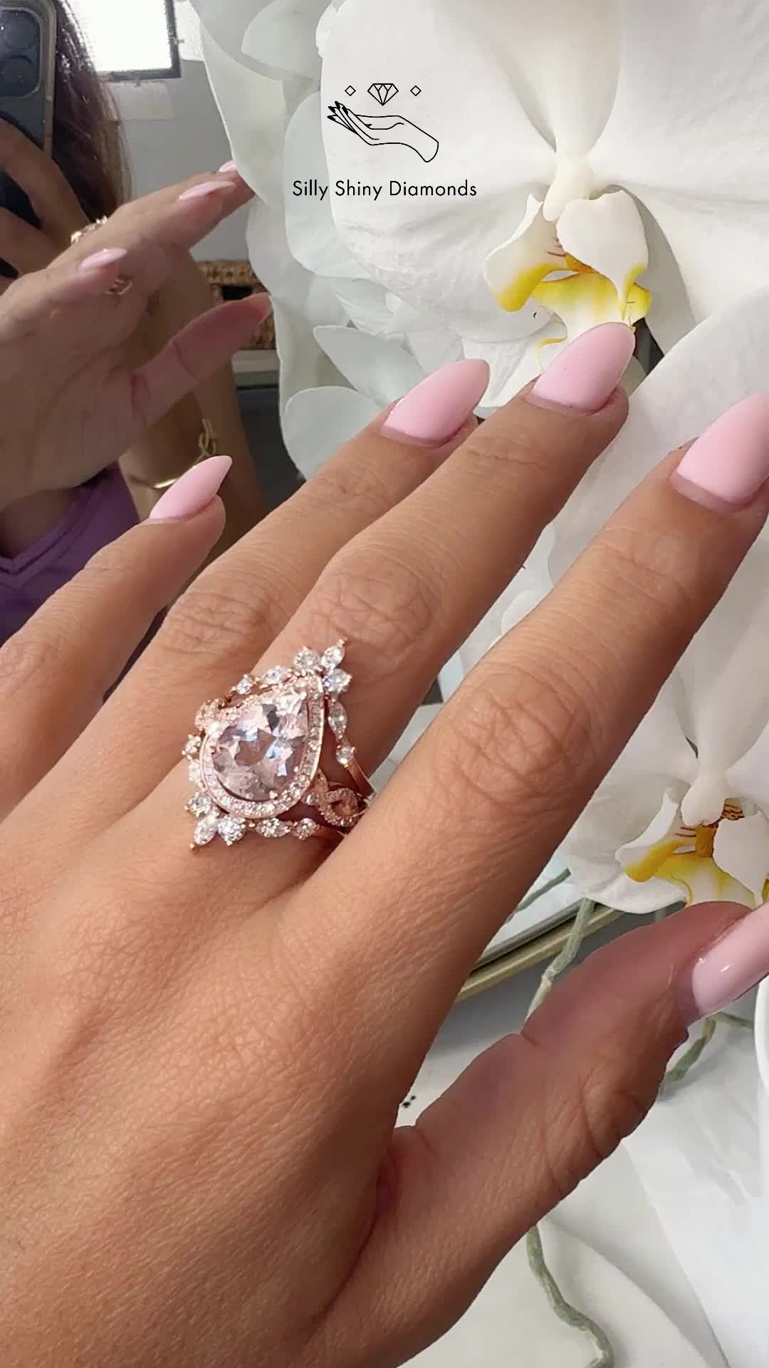 This may contain: a woman's hand with pink manicured nails and an engagement ring on it