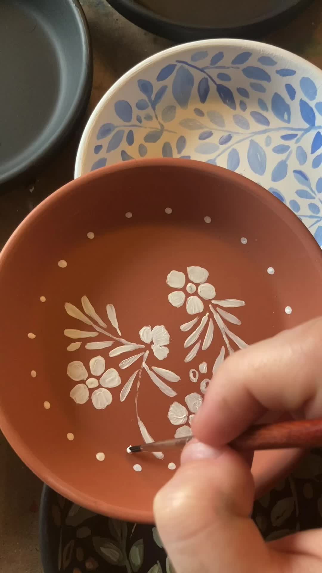 This may contain: many bowls are lined up together on the table, one is painted with floral designs