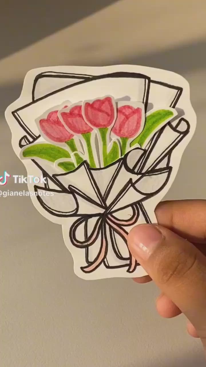 This may contain: a hand holding up a sticker with flowers on it