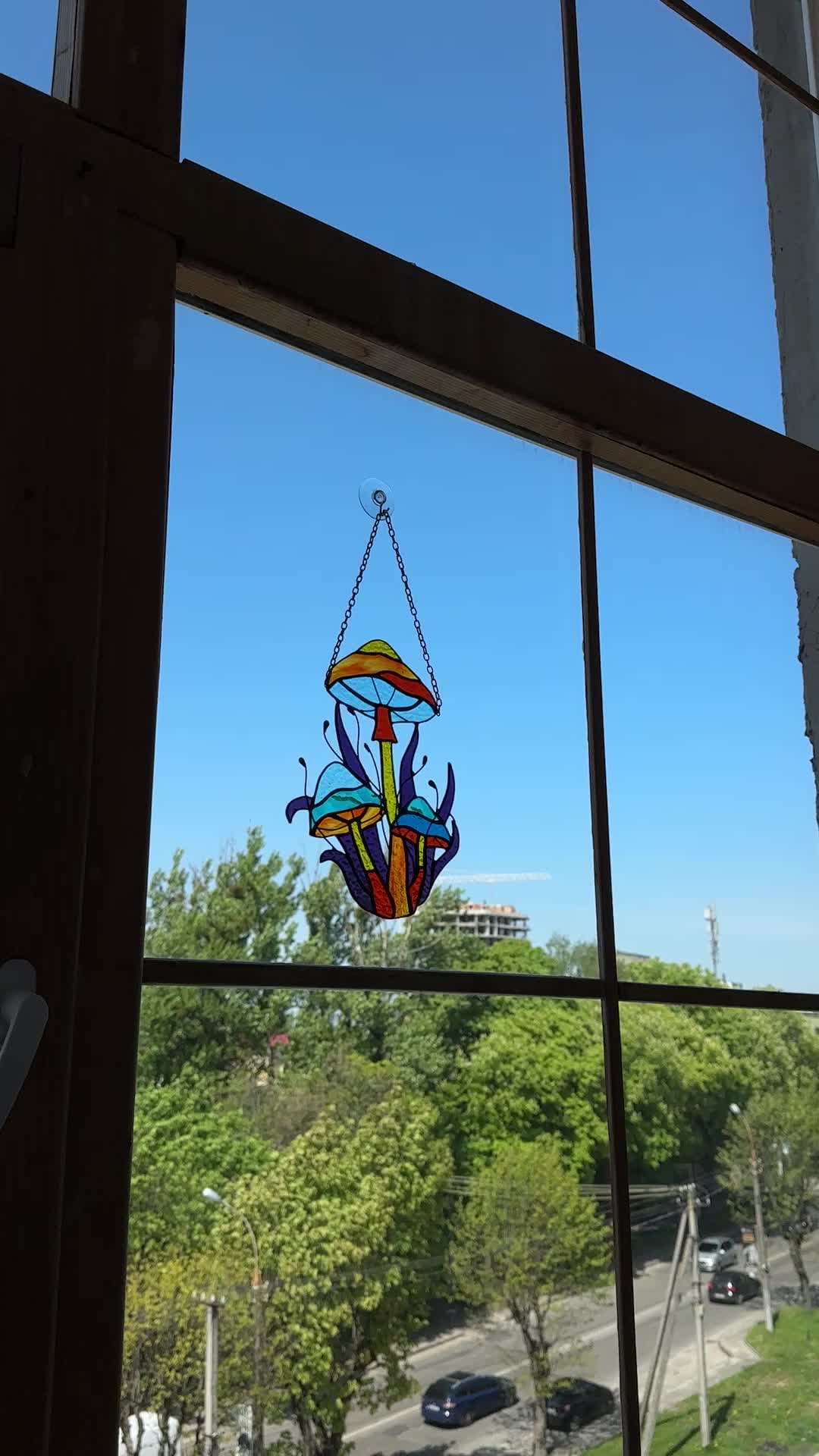 This may contain: a stained glass window with an umbrella hanging from it's side and trees in the background