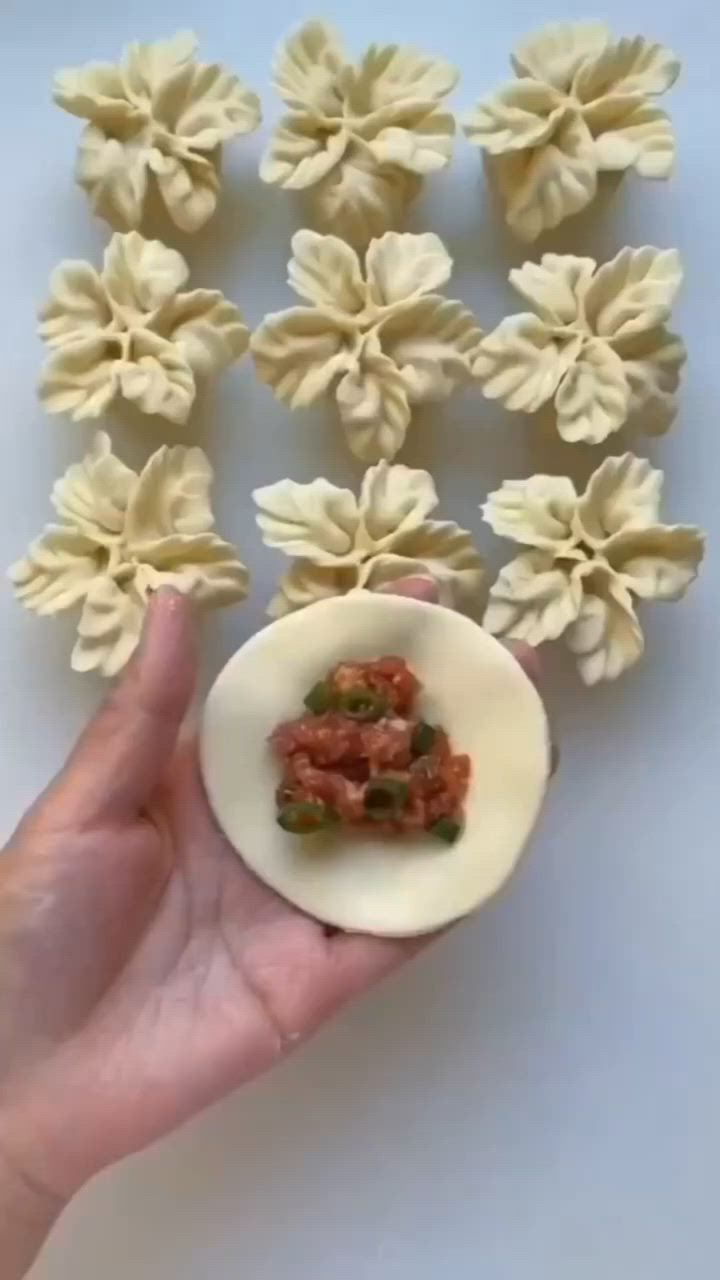 This may contain: a hand holding a small bowl filled with pasta shells and toppings on top of it