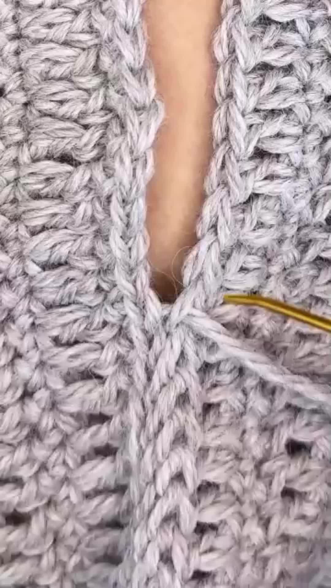 This may contain: closeup of the crochet stitches on a knitted sweater that is being sewn