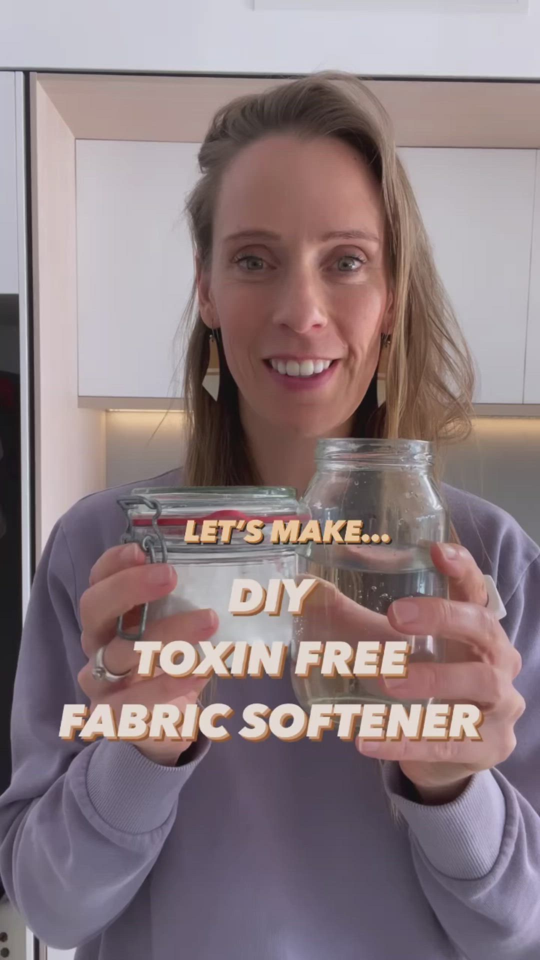 This may contain: a woman holding up a jar filled with fabric softeners