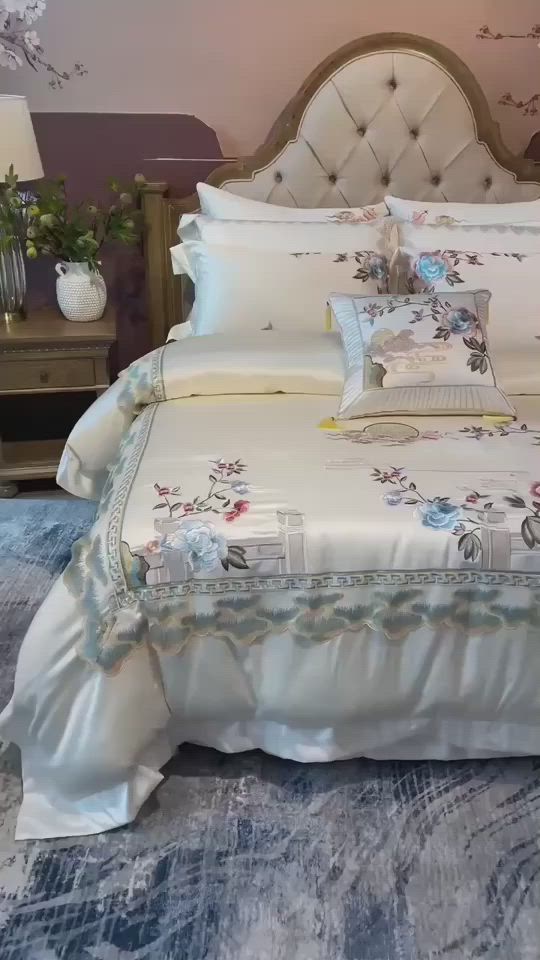 This may contain: a bed with white comforter and pillows on top of it next to a night stand