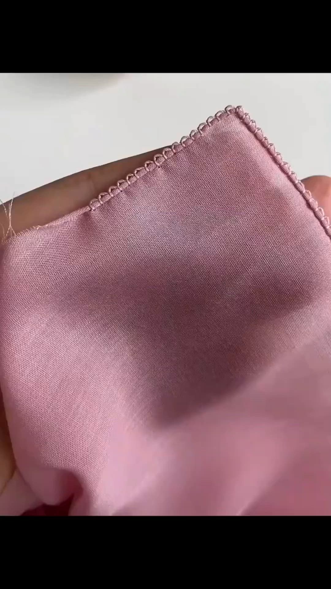 This may contain: someone is stitching something on the pink fabric