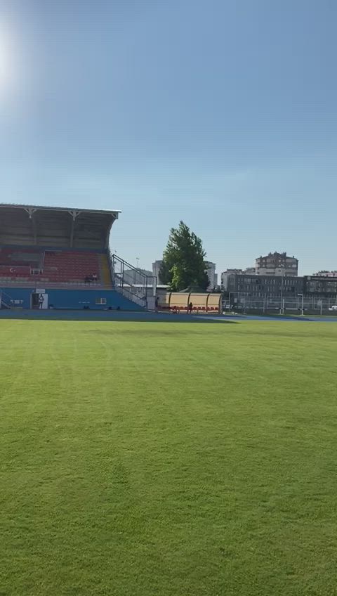 This may contain: an empty soccer field with the sun shining on it