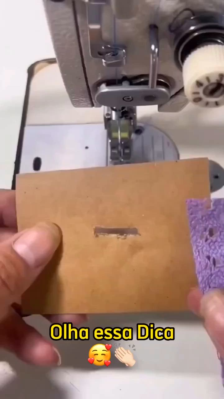 This may contain: someone is using a sewing machine to sew something on the piece of paper that they are holding