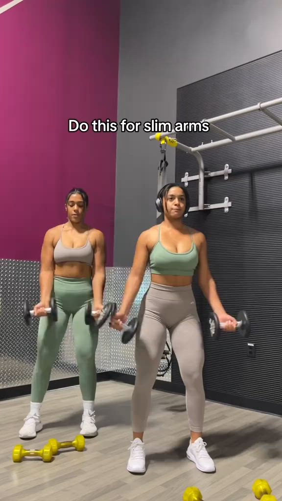 This may contain: two women are doing exercises with dumbbells in the gym while holding their arms up