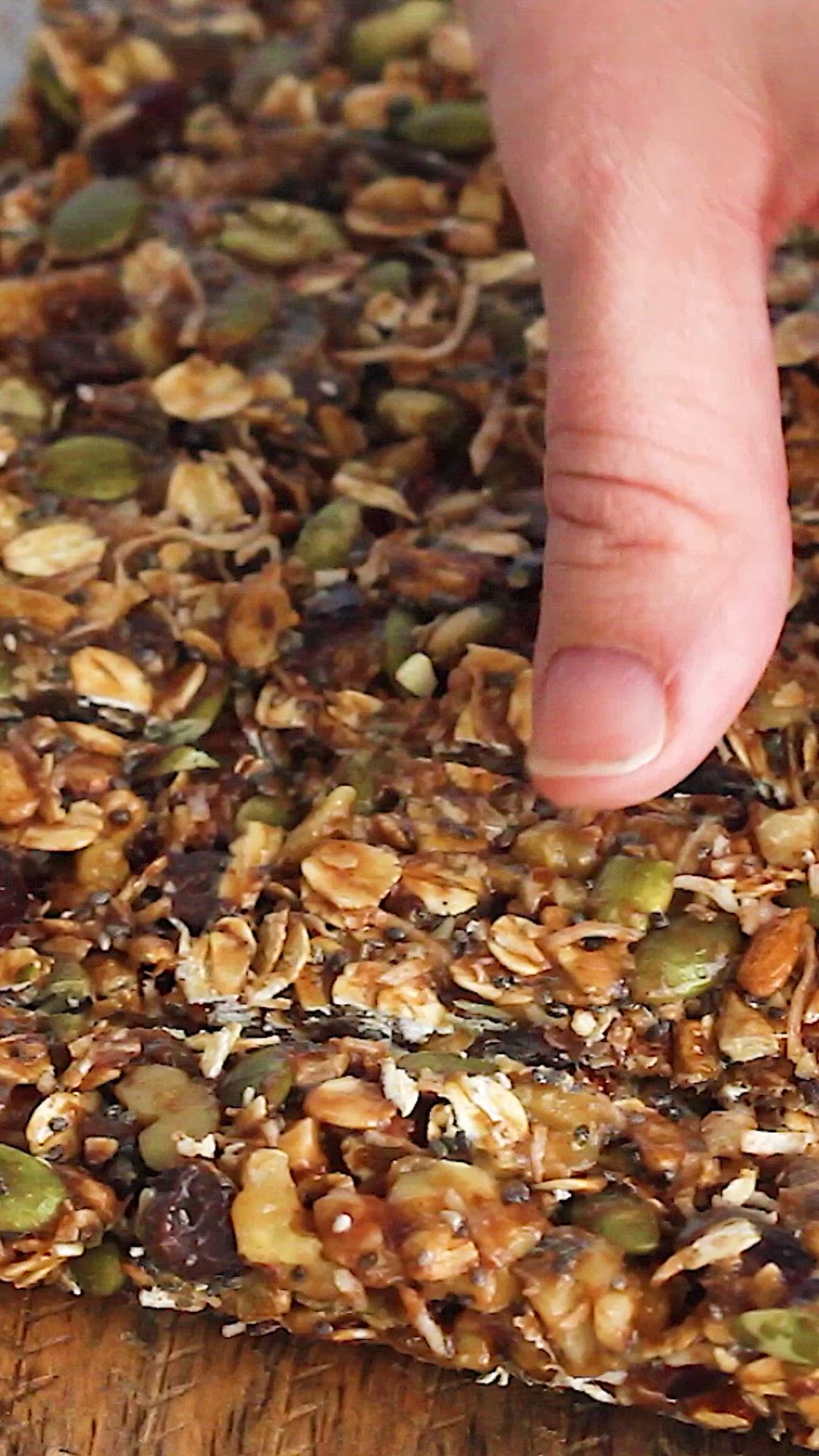 This may contain: a person reaching for granola on top of a wooden table