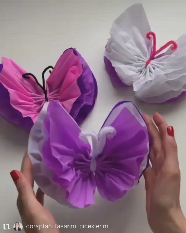 This may contain: three pieces of tissue paper are being made into butterfly shaped hair clips, one is pink and the other is white