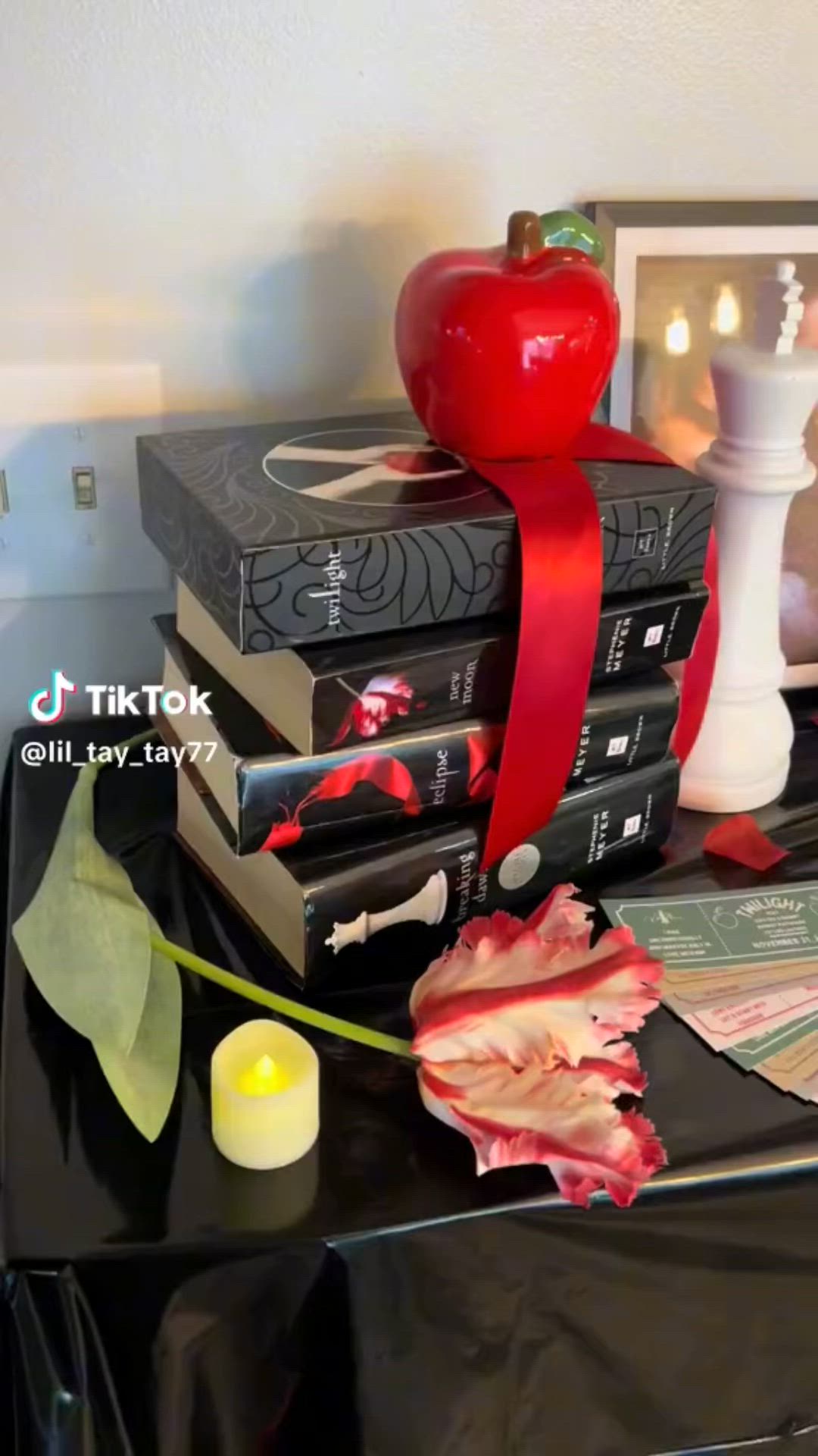 This may contain: a stack of books sitting on top of a table next to a candle and an apple