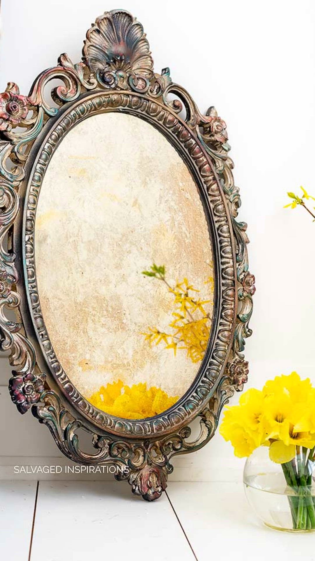 This may contain: a mirror sitting on top of a table next to a vase filled with yellow flowers