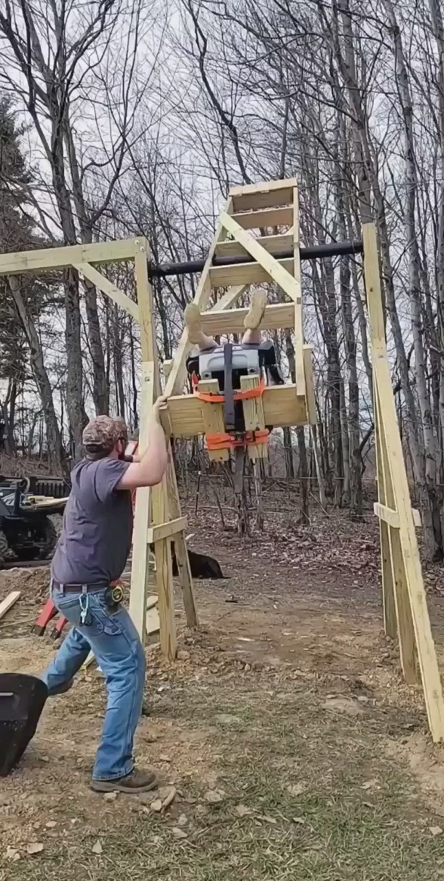 This may contain: two people are playing in the woods with an obstacle set and equipment for children to play on