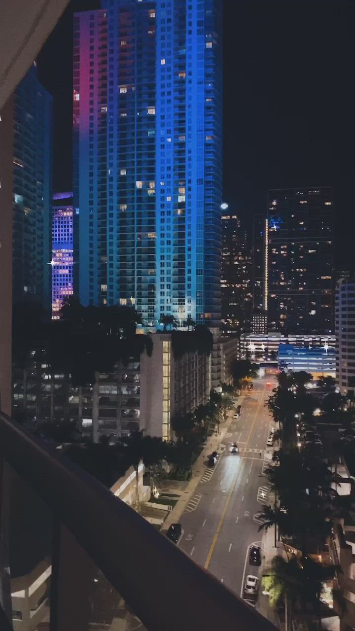 This may contain: a city street at night with tall buildings in the background