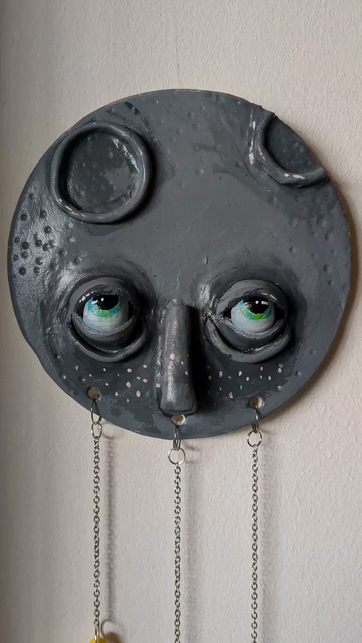 This may contain: a clock with eyes and chains hanging from it's face on the wall,