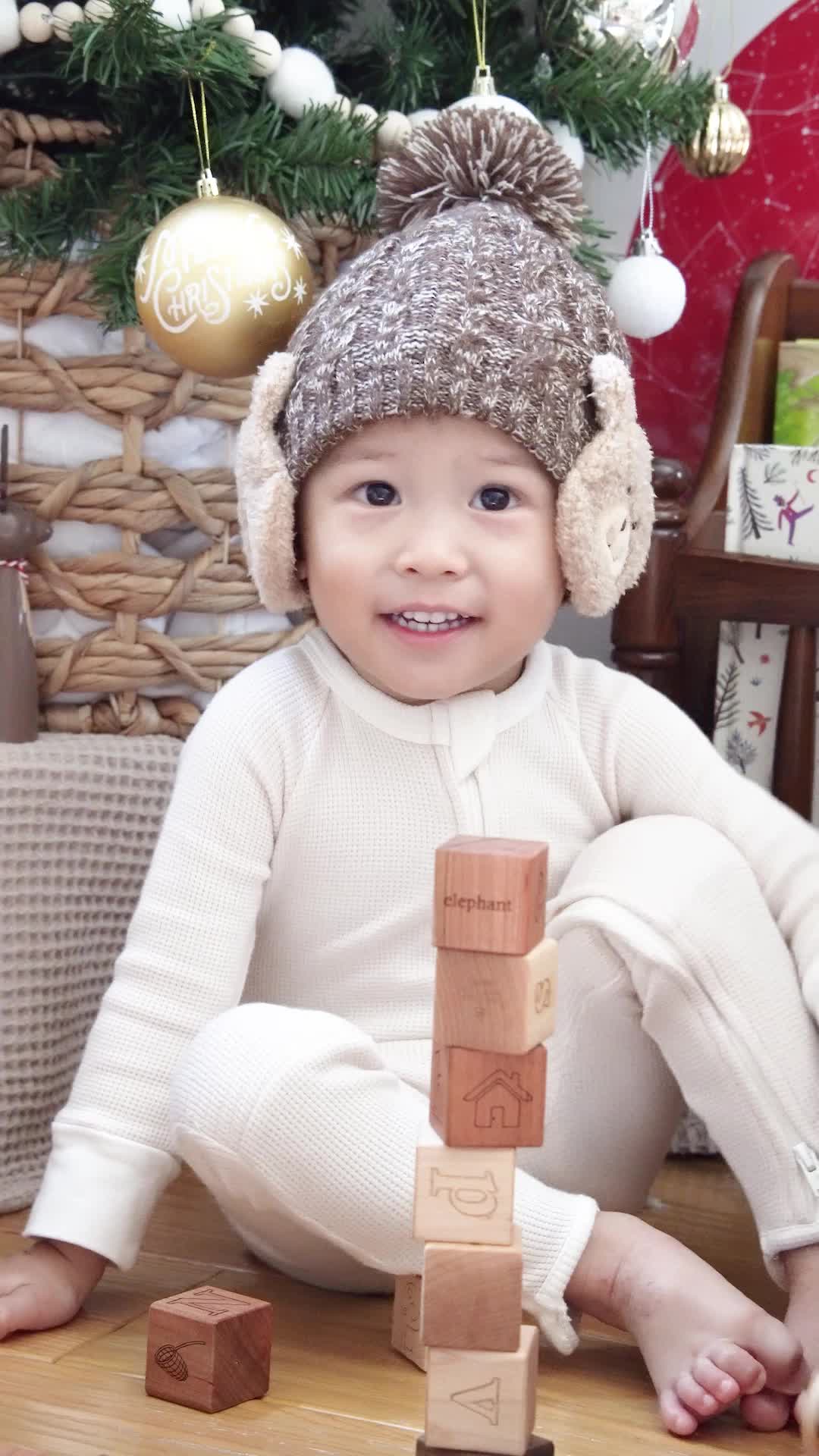 This may contain: a baby is playing with wooden blocks in front of a christmas tree and other decorations