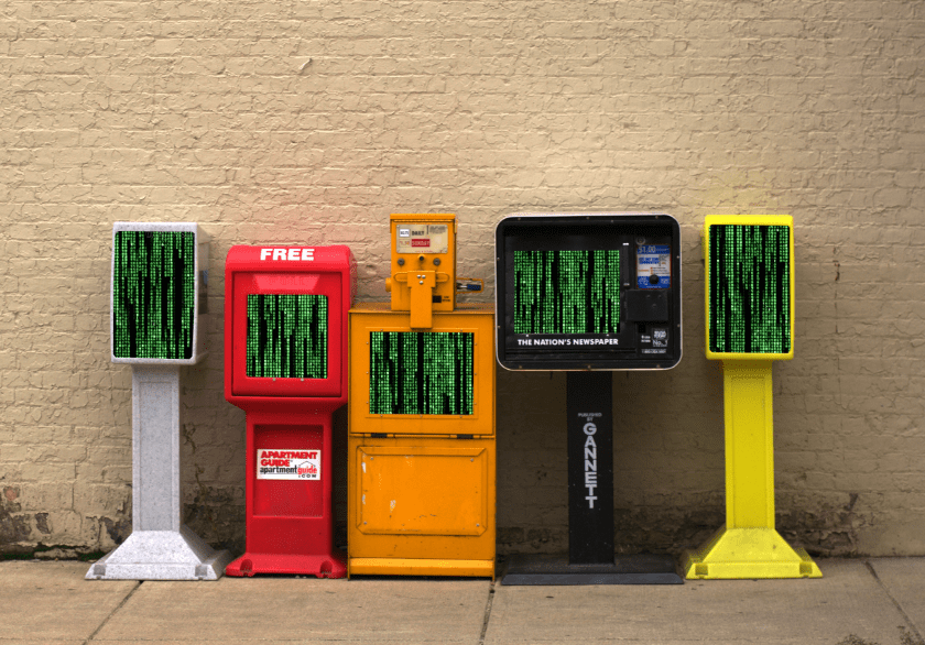 A row of newspaper boxes on a lonely sidewalk; their windows are filled with the 'falling binary' Matrix waterfall effect.