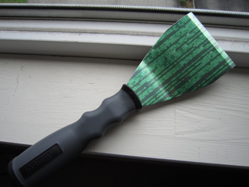 A paint scraper on a window-sill. The blade of the scraper has been overlaid with a 'code rain' effect as seen in the credits of the Wachowskis' 'Matrix' movies.