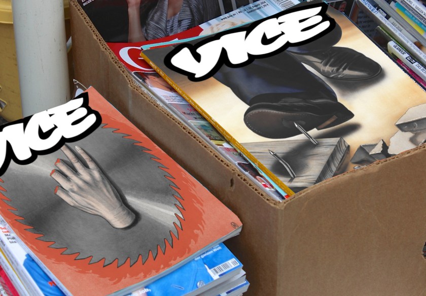 Piles of magazines in boxes. The top two magazines' covers have been replaced with faked up Vice covers. On one, a man's shoe is about to be punctured by a nail sticking up out of a board left on the ground. On the other, a rotary saw blade has amputated several fingers from someone's hand.