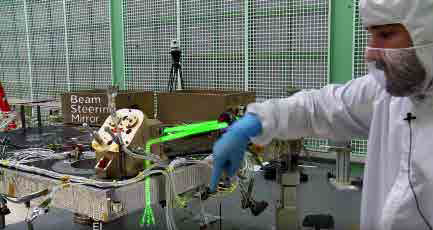 ATLAS engineer Tyler Evans points to the path of the instrument's laser beams (outlined here with drawn-in green lines) as they go through the Beam Steering Mechanism. (NASA)