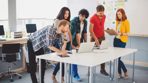 Getty Images Women and men in office on laptops