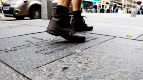 SWNS The boots of a person walking on paving slabs in Inverness city centre