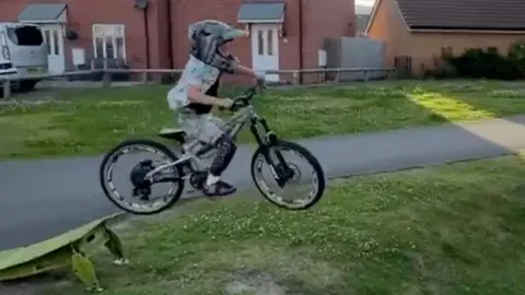 Parker jumping off a ramp on his BMX 