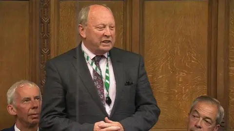Jim Allister speaking in Parliament while Nigel Farage sits beside him