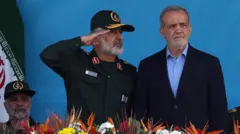 El presidente iraní Masoud Pezeshkian (d) y el comandante de la Fuerza Aeroespacial del Cuerpo de la Guardia de la Revolución Islámica, Amir Ali Hajizadeh (i), asisten a un desfile militar en Teherán, Irán (21 de septiembre de 2024).