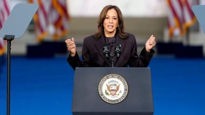 Kamala Harris holds her hands out as she looks at camera while speaking at a lecturn on 6 November