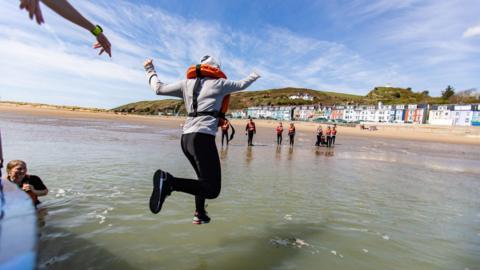 Person jumping off boat into the sea wearing a life jacket 