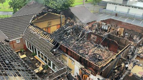 An aerial image of the fire damage caused to the Church of the Holy Name and its adjacent hall last weekend.   The image shows that large section of the roof had collapsed and charred embers fill the remaining structure.