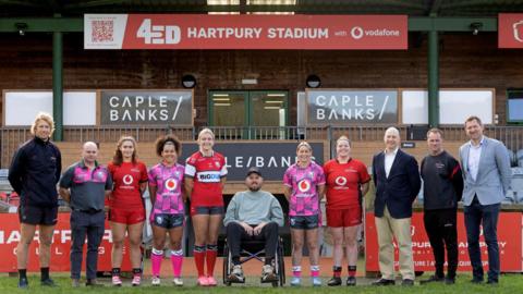 Ed Slater (centre) with Gloucester-Hartpury players and coaches including Billy Twelvetrees (far left), co-captain Natasha Hunt (fifth right) and club CEO Alex Brown (far right)