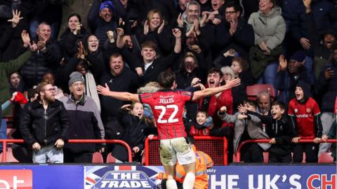 Jamie Jellis celebrates with the delighted Saddlers fans after scoring his fourth goal in the last seven Walsall games to fire his side past Bolton into round two