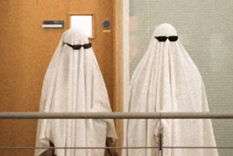 Two people dressed as ghosts with sheets over their body and dark sunglasses covering their eyes