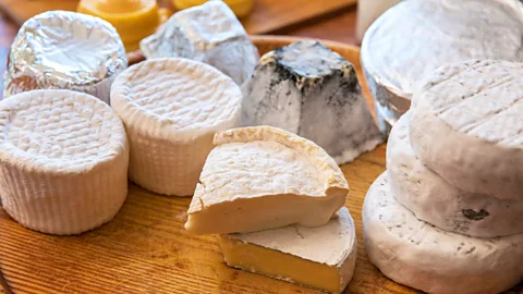 Rounds and wedges of different cheeses on a wooden board (Credit: Alamy)