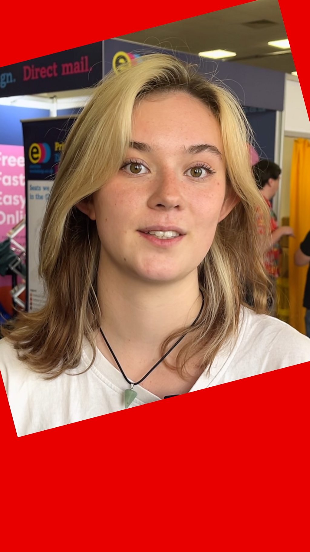 A woman with long blond hair - she wears a white top and a necklace