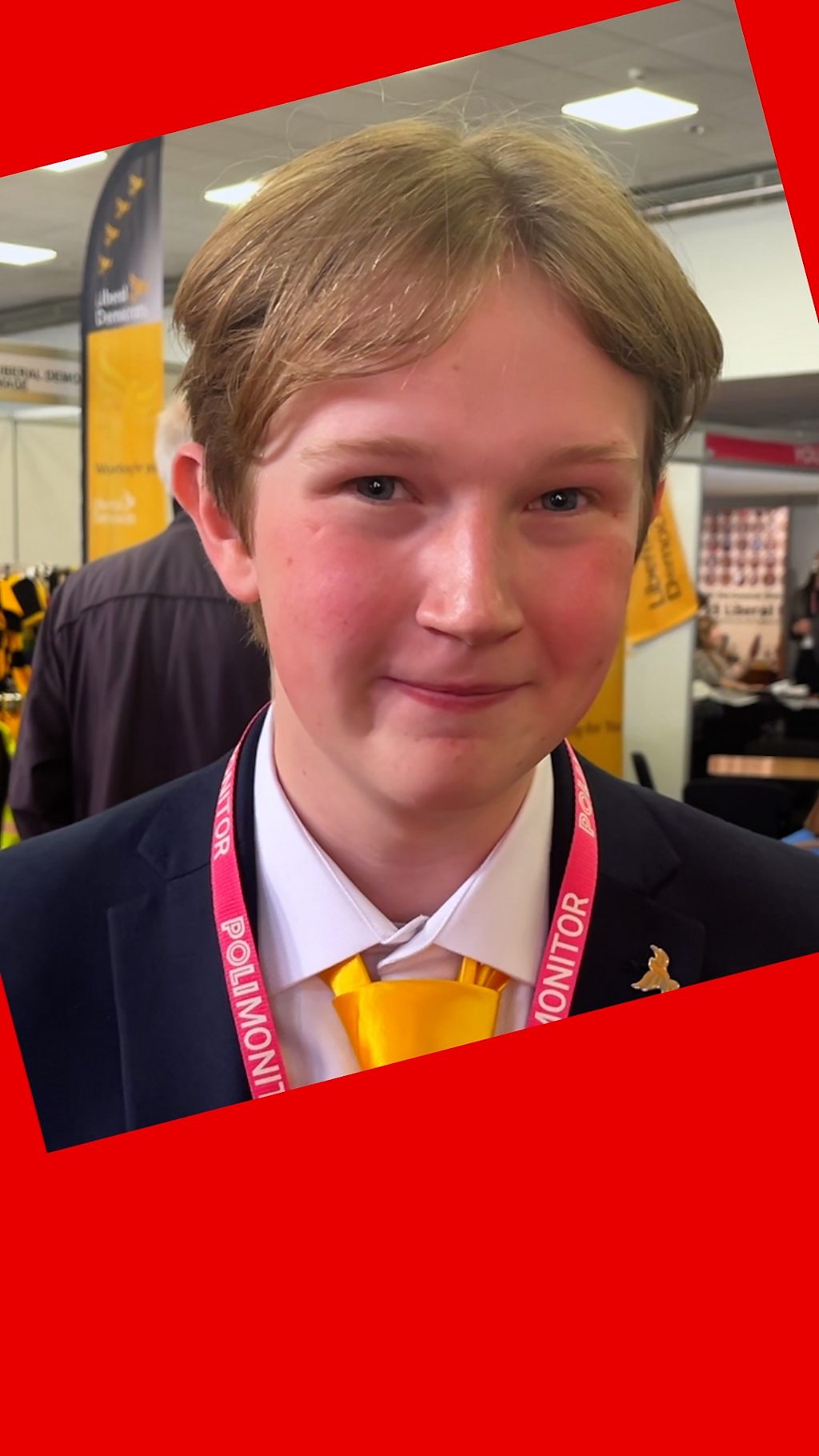 A man with short brown hair - he wears a suit with a yellow tie