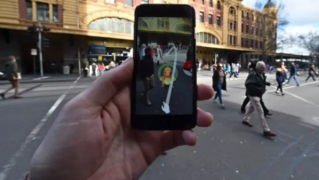 Una persona juega al nuevo Pokemon Go en su móvil, en una calle de Melbourne (Australia). Pokemon Go, con un sistema GPS basado en realidad aumentada, es un juego que está demostrando ser 'enormemente' popular desde que la compañía de desarrollo de software Niantic abrió el acceso a la aplicación el pasado viernes.