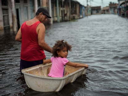 Jesús Hernández con su nieta Angelina en una calle inundada tras el paso del huracán Helene en Batabano, Cuba, en septiembre del 2024.