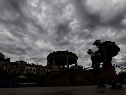 Dos turistas pasean este jueves por la plaza del Castillo de Pamplona con un cielo tormentoso.