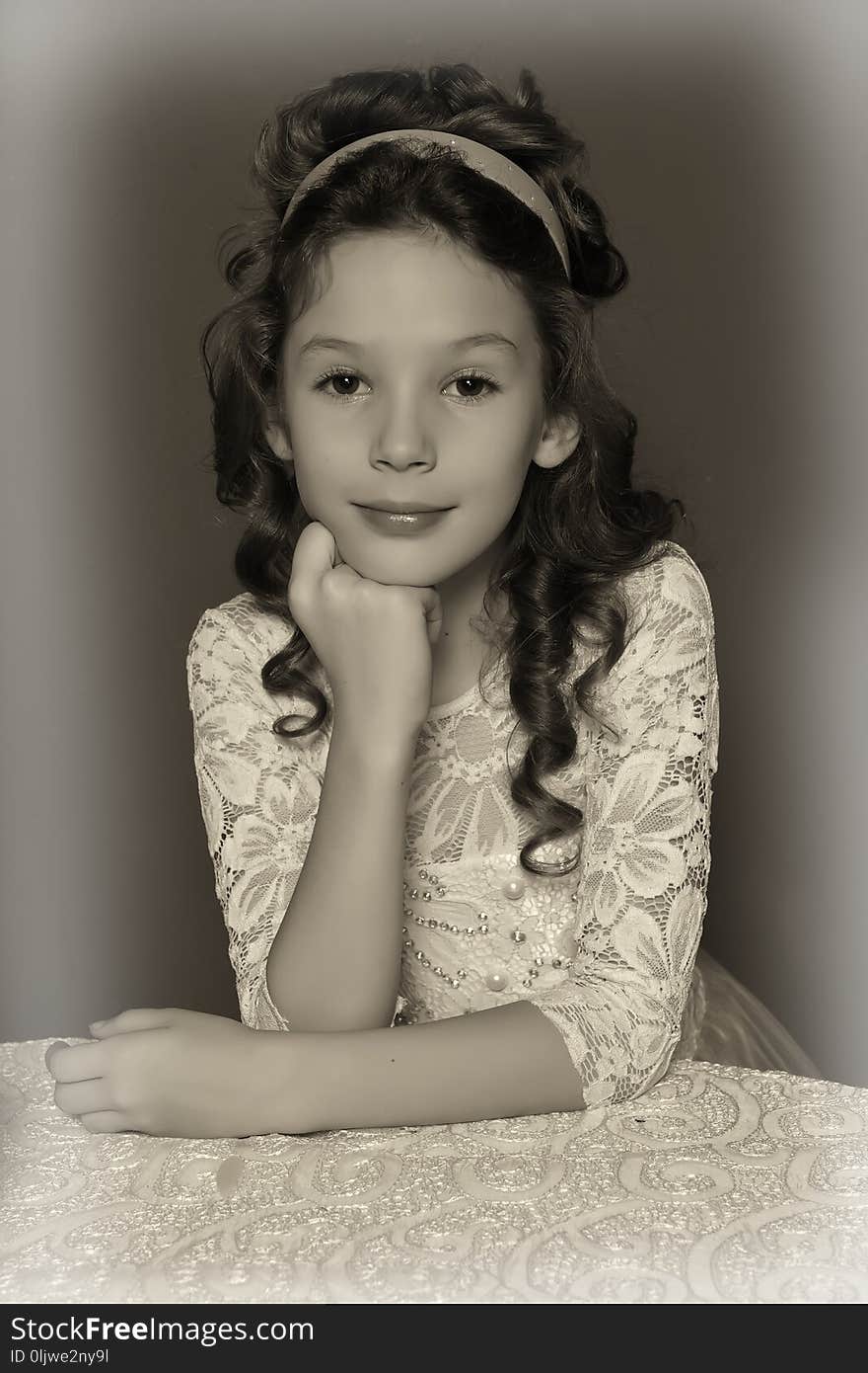 Young girl, a princess standing in a pink retro dress leaning her elbows on the table