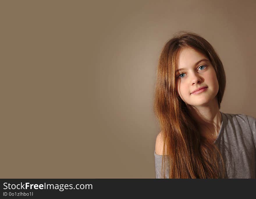 Blue eyed brown haired shy girl with flowing hair on background