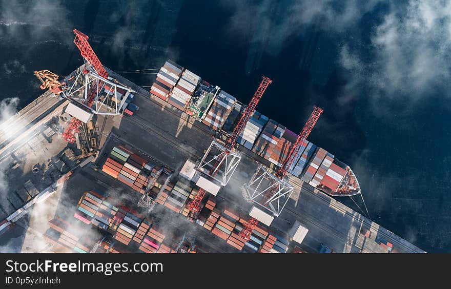 Top view of a cargo ship with containers, which is unloaded in the port. Container Warehouse, Logistics, Cranes, Outdoor, Import and export. Top view. Top view of a cargo ship with containers, which is unloaded in the port. Container Warehouse, Logistics, Cranes, Outdoor, Import and export. Top view