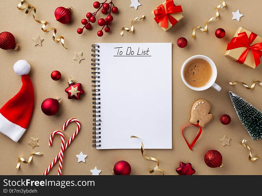 Cup of coffee, holiday decorations and notebook with to do list on golden background top view, Christmas planning concept. Flat lay style