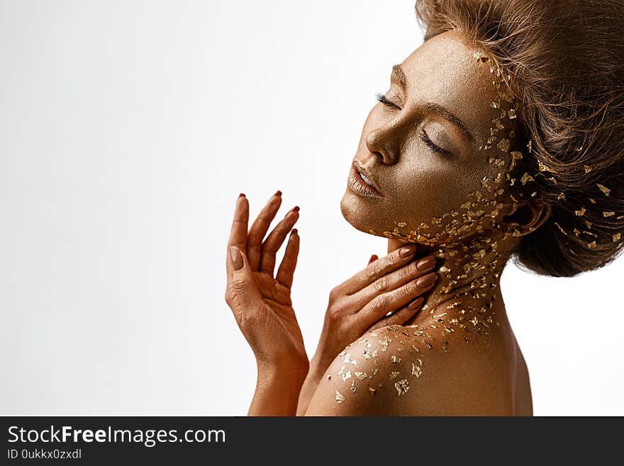 Fashion art portrait of model girl with holiday golden shiny professional makeup. tender woman with gold metallic body and hair. Gold glowing skin. Hairstyle. copy space