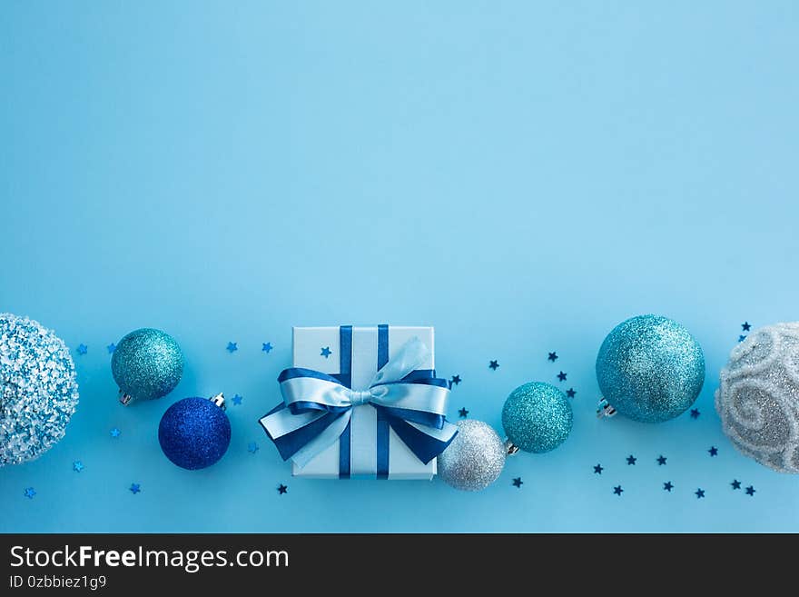 Blue Christmas holiday gift and decor frame on blue background, small decorated box with ribbon bow