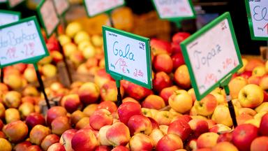 Äpfel verschiedener Sorten stehen an einem Obst- und Gemüsestand. 